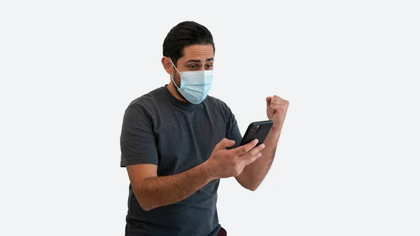 Retrato Homem Caucasiano Alegre Usando Smartphone Máscara Médica Comemorando Com — Fotografia de Stock