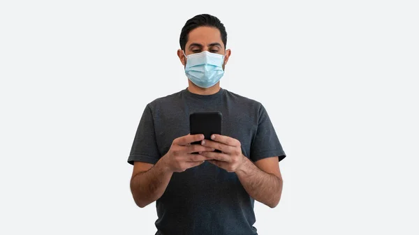 在日冕病毒爆发期间使用智能手机和医疗面罩的高加索男子画像 在白色背景下隔离的室内拍摄室手持电话装置的人 — 图库照片