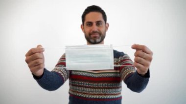 Beyaz arka plandaki stüdyoda steril yüz maskesi kullanan beyaz bir adam. Karantina pandemik koronavirüs virüsü konseptindeki adam..