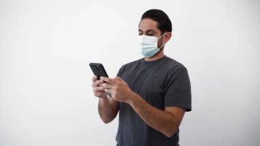 Beyaz arka planda izole edilmiş koronavirüsten korunan akıllı telefon ve yüz maskesi kullanan adam. Elinde telefon cihazı olan biri. Covid-19 pandemik karantina kavramı