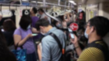 Koronavirüs sırasında Asyalıların bulanık görüşü trende bekliyor ve önlem olarak yüz maskesi takıyor. Akıllı telefonu kontrol eden kişi, Tayvan 'daki istasyona varmayı beklerken...
