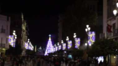 Gece Seville şehir merkezinin kutlamalarında güzel noel ışıkları ve dekorasyonların bulanık görüntüsü. İnsanlarla dolu arka plan kentsel cadde