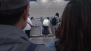Uluslararası havaalanındaki kontrol gişelerinde bekleyen insanların odaklanmış görüntüsü. İş ya da turizm için bavulla seyahat eden Asyalı yolcular. Sahnede bulanık arkaplan