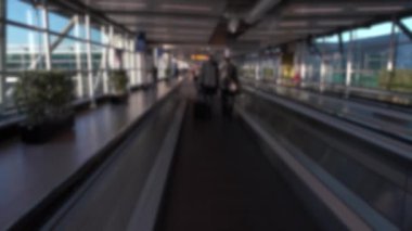 Uluslararası Havalimanı 'ndaki manyetik merdivenlerde bulunan yolcuların bulanık görüntüsü. Modern terminal lobisinin kapısında yürüyen insanlar.