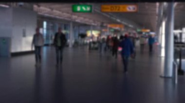 Odaklanamayan yolcular uluslararası havaalanında yürüyor. İnsanlar modern terminal kapılarında uçmak için yürüyorlar. Avrupa havaalanları. Sahnede bulanık arkaplan