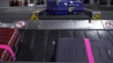 Havaalanı uluslararası terminal binasının varış salonunda valiz taşıma bandındaki bavulun odaksız görüntüsü. Bavul bekleme alanı, yolculuk konsepti