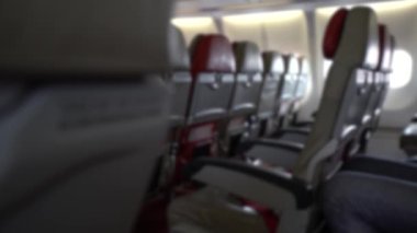 Bulanık, hava yoluyla seyahat ederken odaklanmış. İç uçaktaki koltukların olduğu kabin. Koltuktan yolcu olarak bakış açısı. Gezginler uçağa biniyor. Uçağın içinde..
