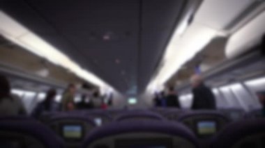 İç uçağın odak dışı görüntüsü, koridordaki yolcular uçaktan inmek için yürüyorlar. İş ya da turizm için bavulla seyahat eden insanlar. Erkek ve kadın yolcular. Bulanık arkaplan