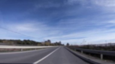 İspanya 'nın kırsal kesimindeki uzun yolda araba sürerken POV görüntüsünün odaklanmış görüntüsü. Açık ve güneşli bir günde İspanyol arazisi. Sahnenin arka planı bulanık. Bulanık arkaplan