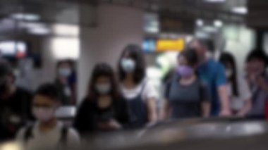 Metroya giden yürüyen merdivende bulaşıcı hastalıklara karşı koruyucu maske takan bulanık Asyalı insanlar tren istasyonuna gidiyor. Coronavirus koruması