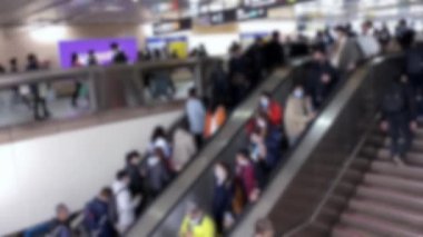 Metroya giden yürüyen merdivende bulaşıcı hastalıklara karşı koruyucu maske takan bulanık Asyalı insanlar tren istasyonuna gidiyor. Coronavirus koruması