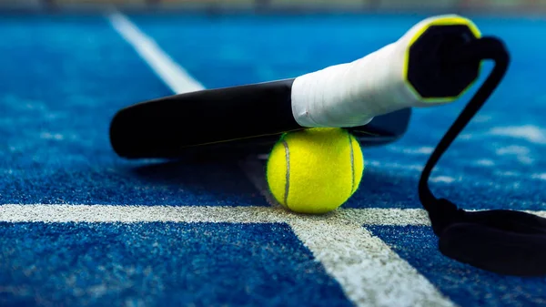 青いコートの屋外でパドルネットの後ろの床にラケットを黄色のボール パデルテニスはラケットゲームです プロスポーツのコンセプト — ストック写真