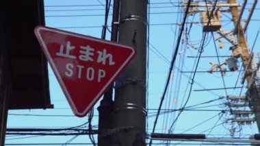 Kırmızı üçgen trafik işaretini uyarı levhası üzerinde beyaz harflerle kanji Japonya 'daki yerel sokak kavşağında duruyor. Kelimenin Japoncada çevirisi dur demektir.