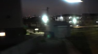 Japonya 'da gece vakti tren seyehatinin penceresinden şehir manzarası. Tren istasyonundan kalkan trenler. Nara 'da geleneksel ev yapımı Japon caddesi.