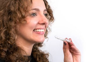 Gülümseyen güzel yetişkin kadın elinde şeffaf diş telleri tutuyor. Beyaz adam görünmez ortodontik diş teli ve hizalayıcı tutuyor.
