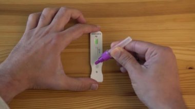 Örneği covid-19 antijen test cihazına yerleştiren adam negatif sonuç verdi. Beyaz adam evde negatif Coronavirüs testi gösteriyor..