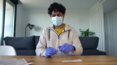 Lateks eldivenli bir adam Covid19 için antijen teçhizatıyla kendi kendine test yapıyor. Coronavirus enfeksiyonunu kontrol etmek için tampon damlatıcıya burun sopasıyla giriyoruz. Karantina salgını.