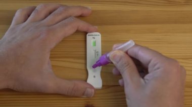 Adamın yavaş yavaş evdeki koronavirüsü tespit etmek için numuneyi tampon damlatıcıya koyması. Kalabalıktan döndükten ve insanlarla tanıştıktan sonra PCR testi. Karantina salgını.