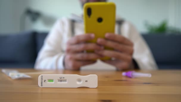 Muž Používající Svůj Chytrý Telefon Provedení Antigenového Diagnostického Testu Negativním — Stock video