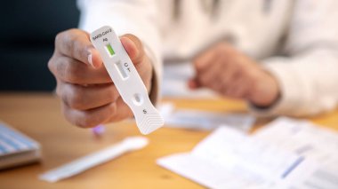 Evde koronavirüsün tespiti için tampon düşürücü tutan bir adam var. Yeni Omicron varyant virüsü için PCR ekspres testinin antijen kaseti. Karantina salgını.