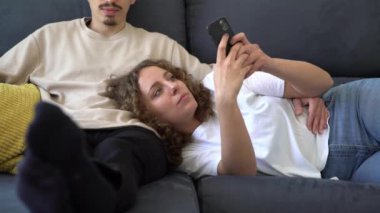 Çift rahat bir dairede kanepede dinleniyor. Erkek arkadaşı televizyon izlerken bir kadın telefonuyla vakit geçiriyor. Teknoloji ve internet bağımlılığı kavramı