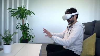 Kafkasyalı bir adam rahat evdeki kanepede otururken sanal gerçeklik gözlüklerinin tadını çıkarıyor. Video oyunu oynayan mutlu adam vr kulaklık ya da 3D gözlük kullanıyor.
