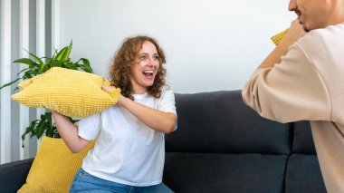 Erkek arkadaşları sabah evde yastık savaşı yapıyor. Mutlu gençler birlikte vakit geçiriyorlar. Neşeli bin yıllık yaşam tarzı ve komik ilişki konsepti. Kadın yüzüne odaklan.