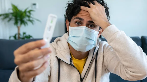 テストを保持マスクを身に着けている不幸な男はCovi19のための肯定的な結果を示した 自己検査コロナウイルスの抗原検査キットを作った後 思考の中で失われた悲しい人 検疫パンデミックにおけるPcr — ストック写真