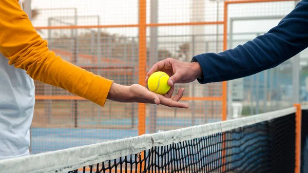 ネット上で対戦相手からテニスボールを受け取るパデル選手の男性の手 男はオープンブルーコートで試合をプレイ — ストック写真