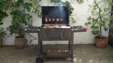 Barbekü ızgarasında tatlı patatesli domuz pirzolası pişiriyorum. Izgarada domuz eti pişir. Evin arka bahçesinde ızgarayla pişirilen yemekler.