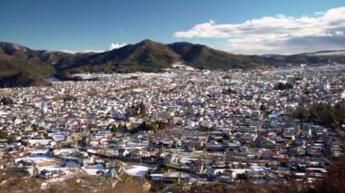 Fujiyoshida Japon şehrinin havadan görünüşü. Ufuktaki dağlarda bitkiler ve binaların etrafındaki parklar var. Japonya 'nın eski kentinin manzarası yükseldi.