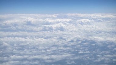 Gökyüzü açık mavi bulutlu harika bir manzara. Beyaz bulutların üzerinde bir uçağın penceresinden görülebilen güzel bir manzara. Uçaktan manzara.