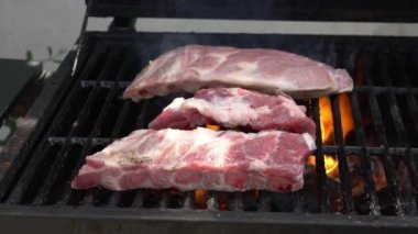 Barbekü ızgarasının üzerinde lezzetli bir domuz pirzolası pişirmenin yavaşlığı. Izgarada domuz eti pişir. Evin arka bahçesinde ızgarayla pişirilen yemekler.