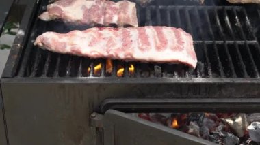 Barbekü ızgarasında domuz pirzolası pişiren şefin yavaşlaması. İspanya 'da tatil tatillerinde mangalda pişirilmiş leziz domuz eti..