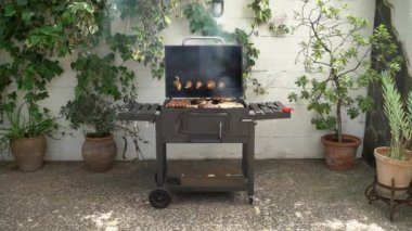 Barbekü ızgarasında tatlı patatesli domuz pirzolası pişiriyorum. Izgarada domuz eti pişir. Evin arka bahçesinde ızgarayla pişirilen yemekler.