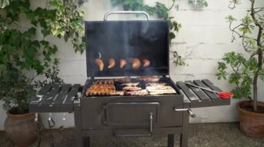 Barbekü ızgarasında tatlı patatesli domuz pirzolası pişiriyorum. Izgarada domuz eti pişir. Evin arka bahçesinde ızgarayla pişirilen yemekler.