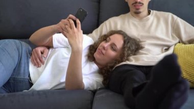 Çift rahat bir dairede kanepede dinleniyor. Erkek arkadaşı televizyon izlerken bir kadın telefonuyla vakit geçiriyor. Teknoloji ve internet bağımlılığı kavramı