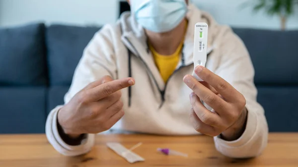 Covid19ウイルスの迅速な家庭用テスト装置に手を指している悲しい原因不明の男 Pcrの抗ゲンカセットから新しいOmicronバリアントウイルス — ストック写真