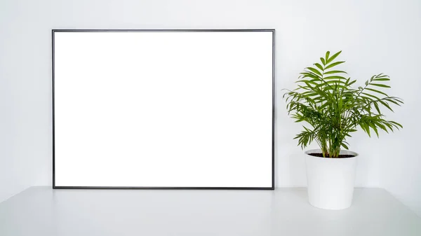 White poster on table with black frame and plant mockup for you design. Layout mock up good use for your design preview. Frame mock-up with copy space.
