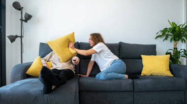 Erkek arkadaşı rahat bir dairede televizyon izlerken kadın savaşa hazırlanıyor. Çift evdeki kanepede oynarken eğleniyor. Yastıkla kavga ediyor..