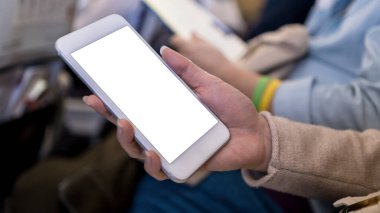 Uçuş sırasında akıllı telefonun bir kopyası. Tasarım önizlemeniz için düzenleme hazırlansın. Kadın uçağın içinde elinde telefon cihazıyla oturup uçakta bir mesaj gördü..