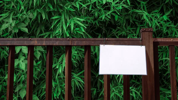 Mockup of sign on fence with bamboo wood forest, natural background. Layout mock up of protected area ready for your design preview. Billboard mock-up with copy space for logo design presentation.