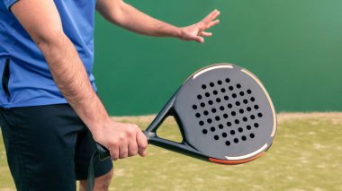 Kürek sporunu yeşil bir kort çimenliğinde siyah bir padel raketle pratik yaparken izleyin. Kürek bir raket oyunudur. Metin için alanı olan profesyonel spor kavramı
