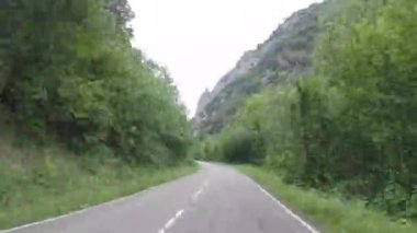 Timelapse driving a car on provincial road passing through a high rocky mountain in Asturias, the north of Spain. Countryside asphalt road landscape surrounded mountains