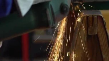 Slowmotion of metal processing with a man using angle grinder to cleaning the steel seam. Locksmith in special clothes and gloves works in production. Sparks in metalworking.