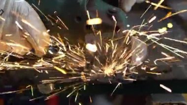 Slowmotion of a man welder with safety clothes polishes the metal angle grinder in the workshop, sideways flashes. Male hands in gloves cut a piece of iron with sparks fly in different directions.