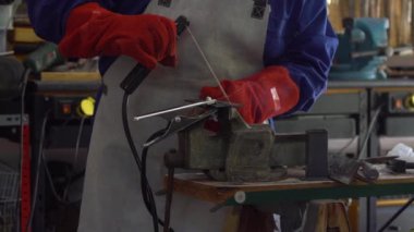 Slowmotion of metal processing with a man using welding machine for steel seam. Locksmith in special clothes works in production. Sparks in metalworking.