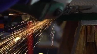Slowmotion of craftsman grinding metal with disk grinder in workshop. Worker cleaning the steel seam. Cutting grinding wheel cut a piece of iron with sparks fly in different directions.