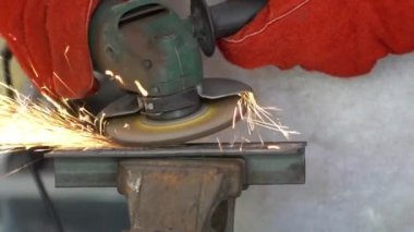 Slowmotion of worker grinding metal with a grinder and cleaning the steel seam. Working in a metal processing workshop. The man works with an electric tool. Sparks from metal heating.