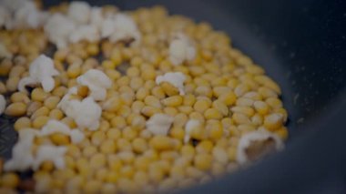 Slowmotion of homemade popcorn popping wildly from a frypan. Crunchy pop corn snack in cooked a pan.  delicious and tasty corns kernels almost popped with salt